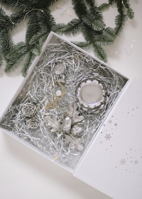 Новогодняя подарочная коробка украшена серебристыми снежинками с набором елочных украшений фото